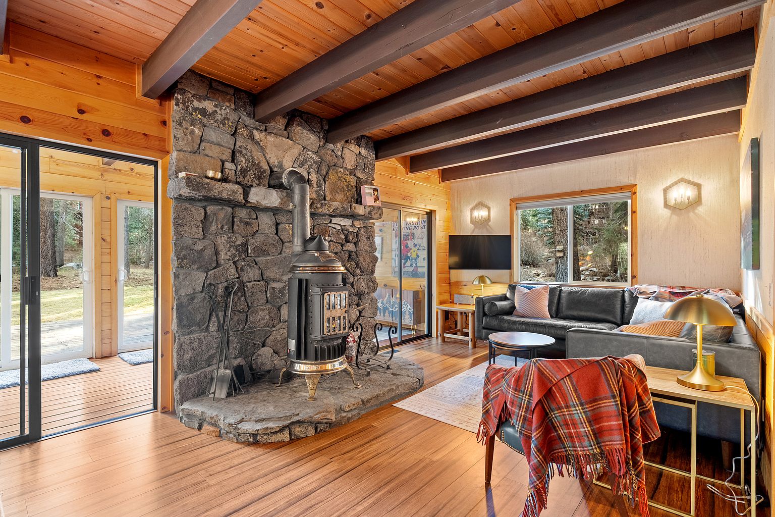 Living room with stone fireplace and vaulted wood ceiling